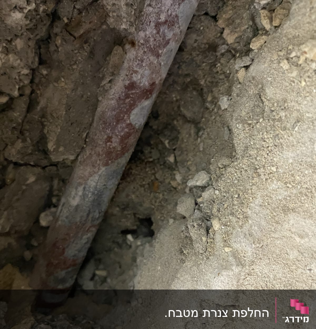 צינור מתכת חלוד בתוך קיר עם בטון מתפורר